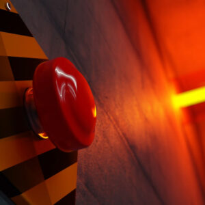 Close up of big red button during emergency situation. Red emergency light flashing in background.